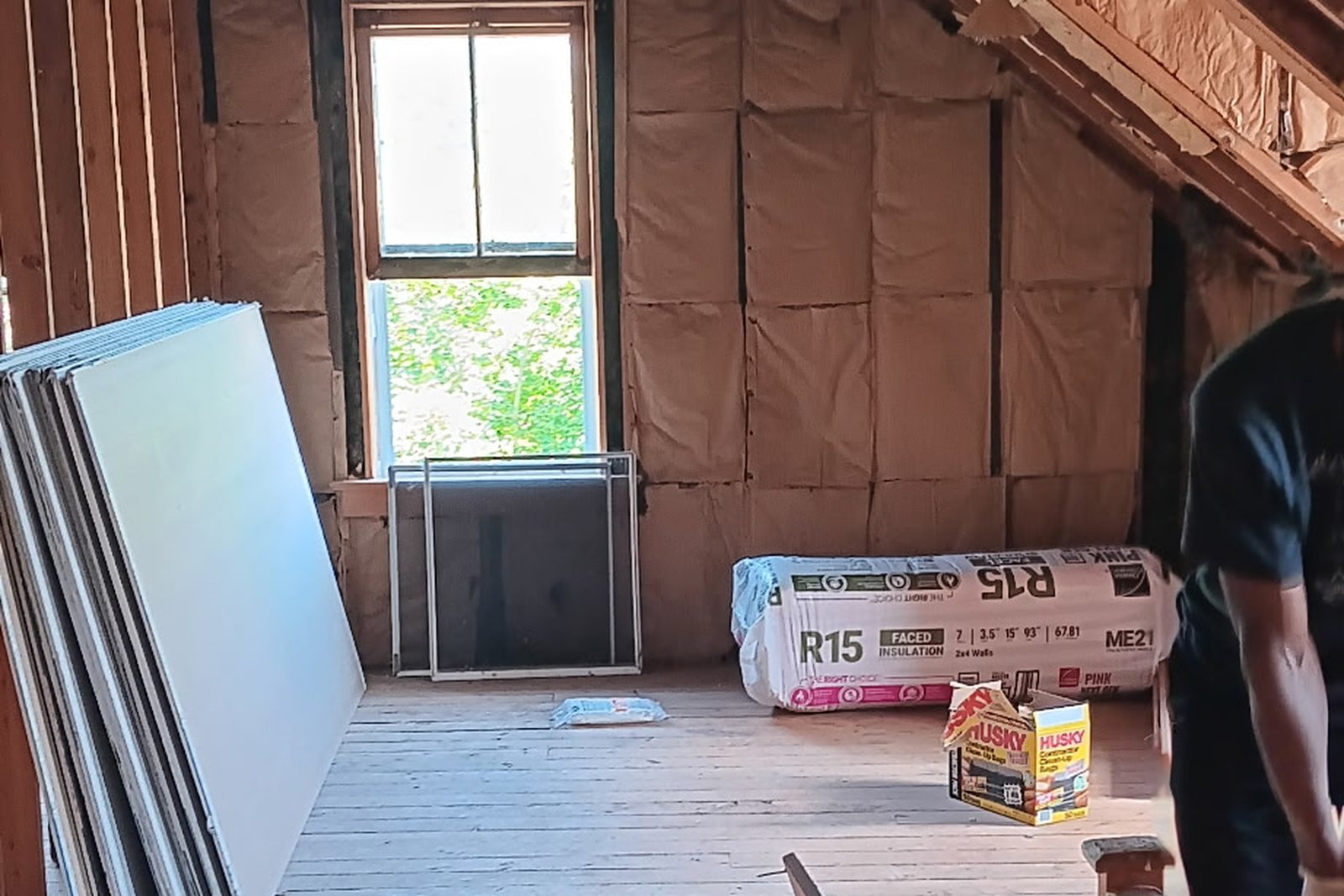 A roof space stripped back to the rafters with insulation open and drywall stacked ready